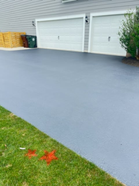 Freshly sealed residential driveway in front of two-car garage