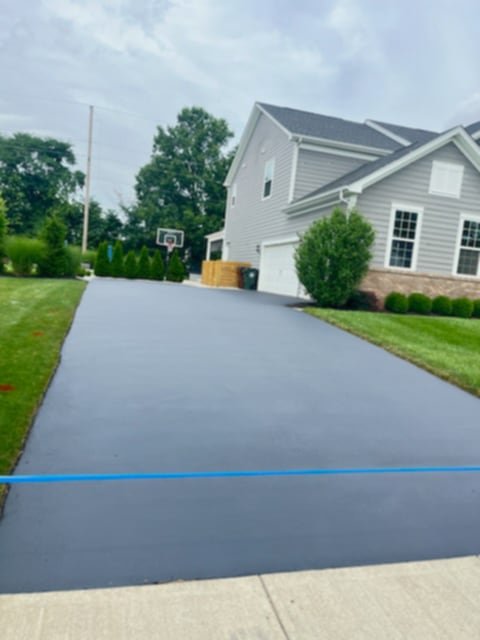 Long driveway with fresh sealcoat leading to modern home